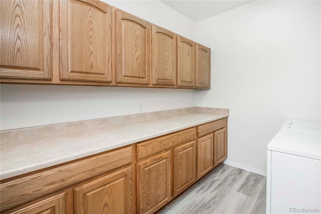 laundry area featuring light hardwood / wood-style floors, cabinets, and washing machine and clothes dryer