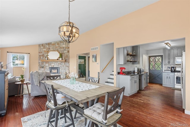 518 Pine Dr, Bailey, CO 80421 - dining room with dark wood finished floors, a chandelier, plenty of natural light, a stone fireplace, and high vaulted ceiling
