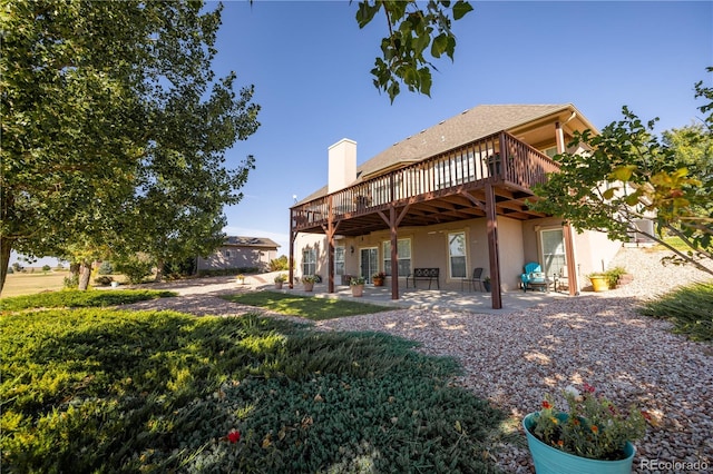 back of house featuring a wooden deck and a patio area