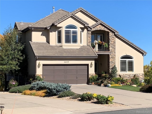 traditional home with an attached garage, stone siding, stucco siding, a tiled roof, and driveway
