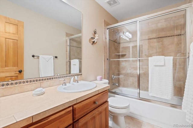 full bathroom featuring visible vents, vanity, tile patterned floors, bath / shower combo with glass door, and toilet