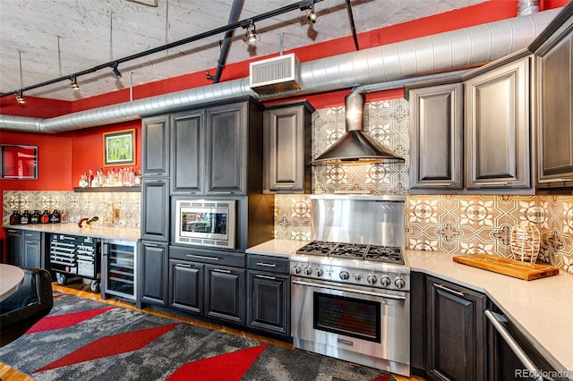 1863 Wazee St Unit 4B, Denver, CO 80202 - kitchen featuring appliances with stainless steel finishes, wine cooler, track lighting, decorative backsplash, and wall chimney exhaust hood