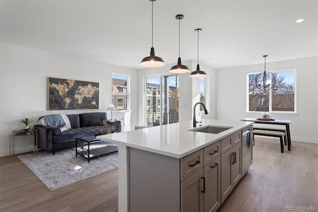 kitchen with sink, an island with sink, hanging light fixtures, and an inviting chandelier