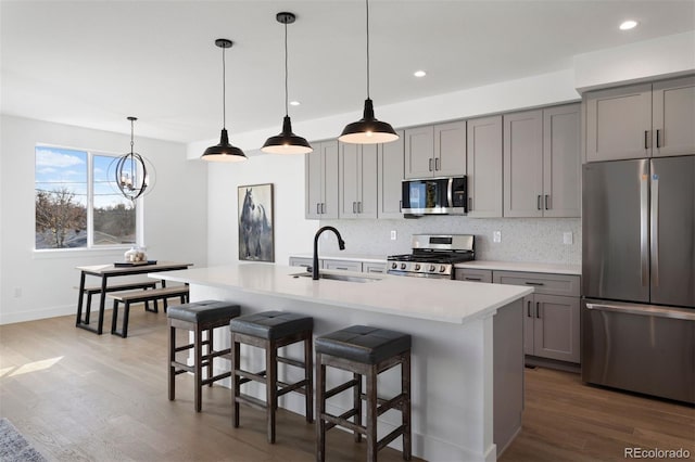 kitchen featuring sink, appliances with stainless steel finishes, gray cabinetry, and an island with sink