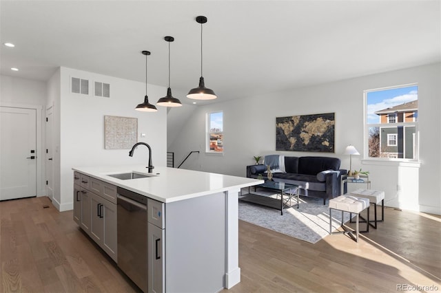 kitchen with pendant lighting, sink, a kitchen island with sink, stainless steel dishwasher, and gray cabinetry