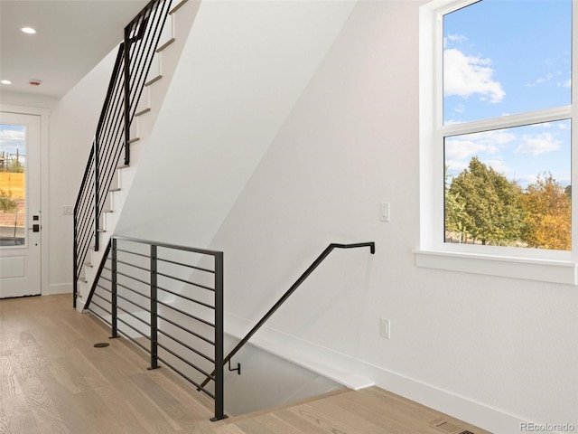 staircase with plenty of natural light and wood-type flooring