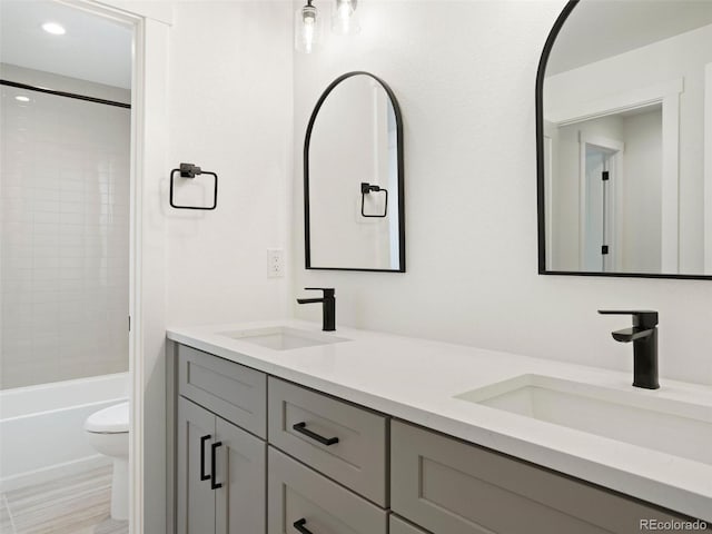 full bathroom featuring tiled shower / bath combo, toilet, and vanity