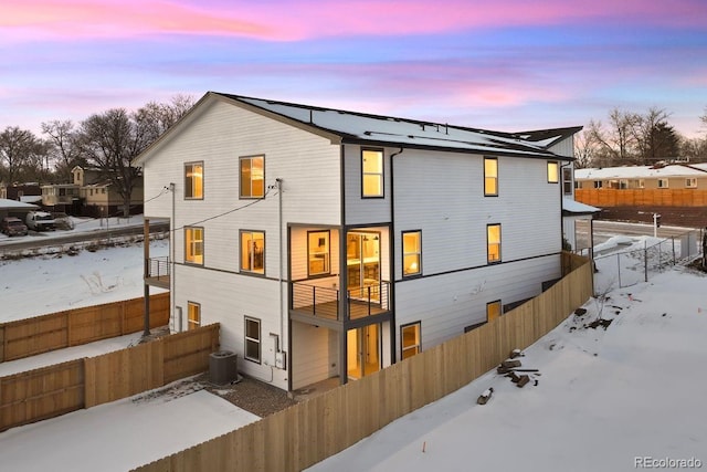 snow covered rear of property featuring central air condition unit and a balcony