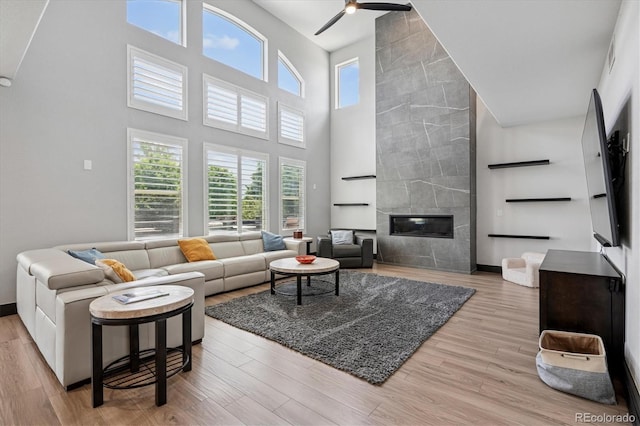 5665 Vistancia Ct, Parker, CO 80134 - living room featuring a high ceiling, ceiling fan, wood finished floors, and a fireplace
