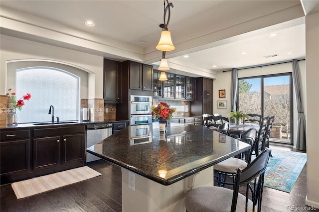 kitchen featuring a sink, dark wood-style floors, a breakfast bar area, and stainless steel dishwasher