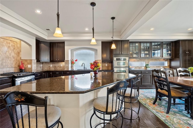 kitchen featuring stainless steel appliances, a tray ceiling, a sink, and dark brown cabinets