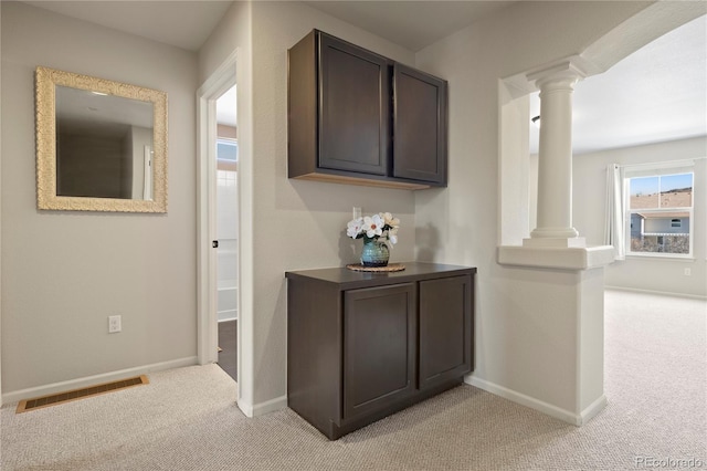 hall with visible vents, decorative columns, light carpet, and baseboards