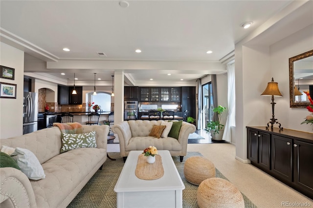 living area featuring light carpet, arched walkways, visible vents, and recessed lighting