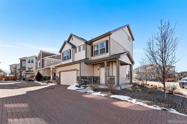 craftsman-style house featuring a garage, stone siding, decorative driveway, and a residential view