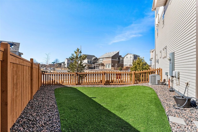 view of yard featuring a fenced backyard, cooling unit, and a residential view