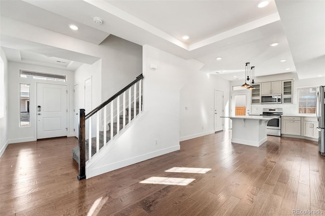 interior space featuring a breakfast bar, light countertops, appliances with stainless steel finishes, a center island, and decorative light fixtures