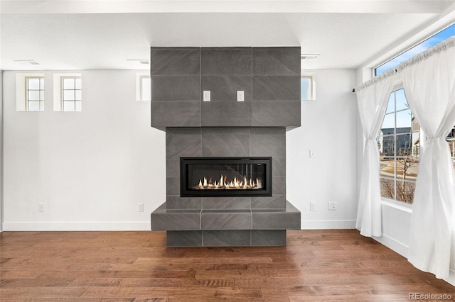 unfurnished living room featuring a fireplace, baseboards, and wood finished floors