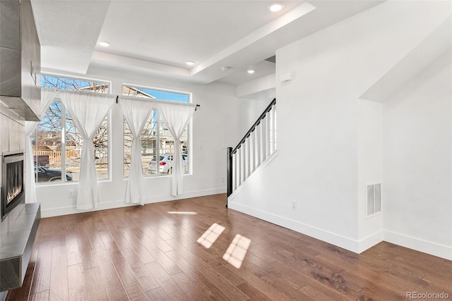 foyer entrance featuring baseboards, visible vents, a raised ceiling, and wood finished floors