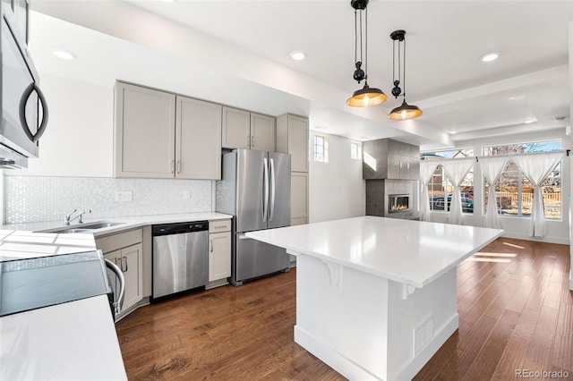 kitchen with light countertops, appliances with stainless steel finishes, gray cabinets, a center island, and pendant lighting