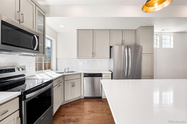 kitchen featuring appliances with stainless steel finishes, dark wood-style flooring, a sink, light countertops, and backsplash