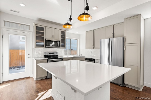 kitchen with stainless steel appliances, light countertops, visible vents, glass insert cabinets, and a kitchen island