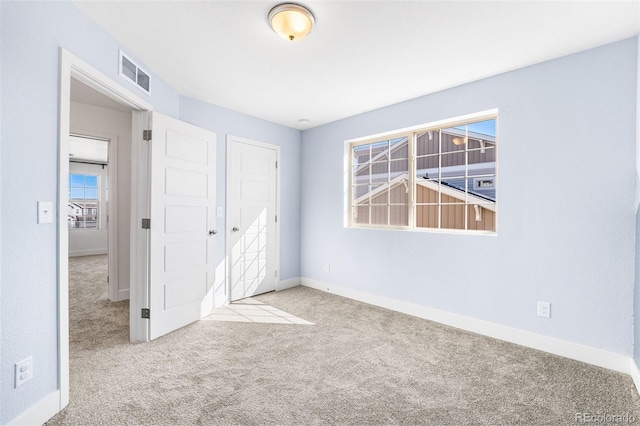 unfurnished bedroom with a closet, light carpet, visible vents, and baseboards