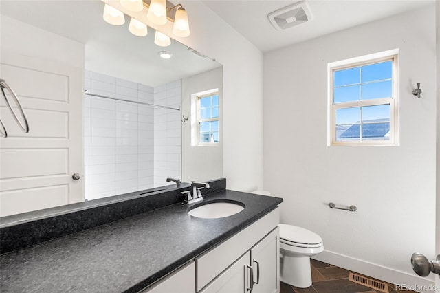 bathroom with toilet, vanity, visible vents, and baseboards