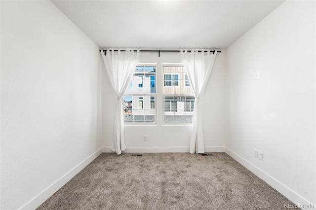 empty room featuring light colored carpet, visible vents, and baseboards