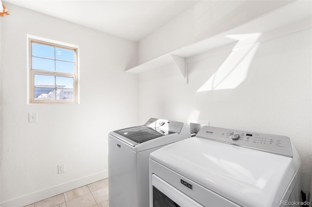 laundry room featuring light tile patterned floors, laundry area, washing machine and dryer, and baseboards