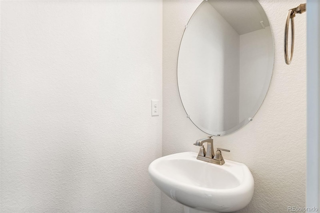 bathroom featuring a textured wall and a sink