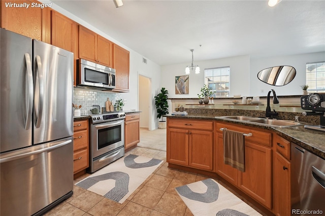 kitchen with pendant lighting, sink, light tile patterned floors, appliances with stainless steel finishes, and backsplash