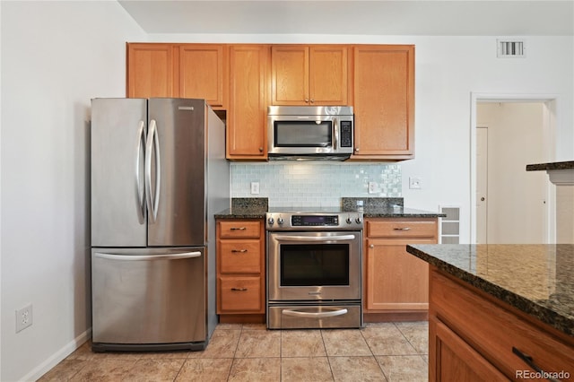 kitchen featuring tasteful backsplash, appliances with stainless steel finishes, light tile patterned floors, and dark stone counters