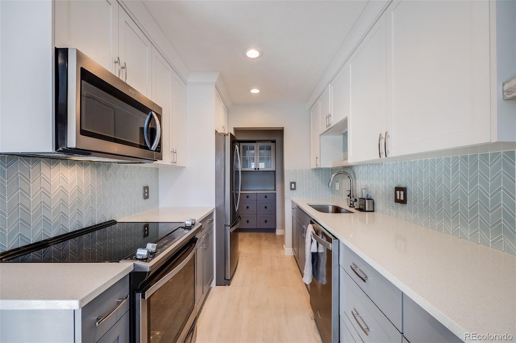 kitchen featuring white cabinetry, sink, stainless steel appliances, gray cabinets, and light wood-type flooring