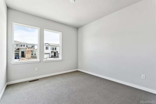 empty room with carpet flooring, baseboards, and visible vents