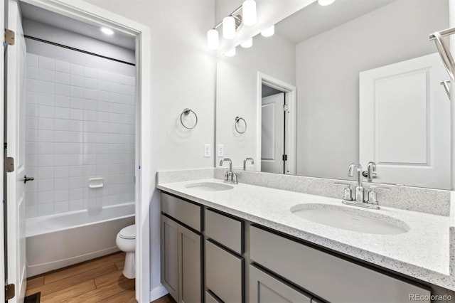 bathroom with double vanity, toilet, wood finished floors, and a sink