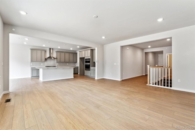 unfurnished living room featuring light wood finished floors, visible vents, recessed lighting, and baseboards