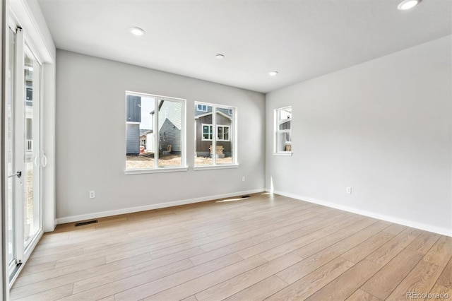 empty room with light wood finished floors, recessed lighting, and baseboards