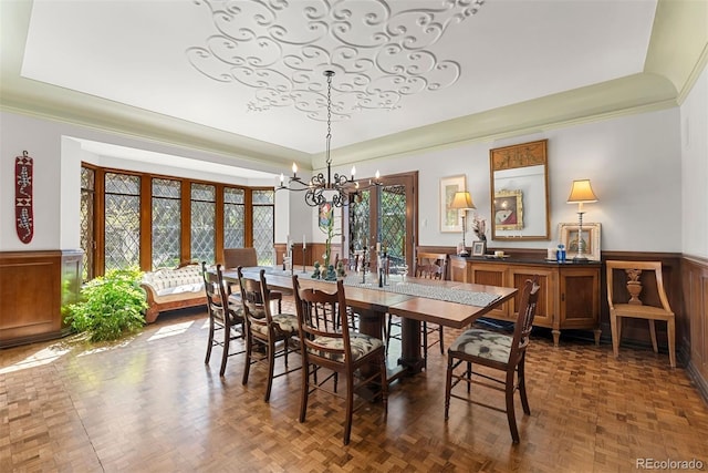 dining area featuring a wainscoted wall, a tray ceiling, ornamental molding, and an inviting chandelier