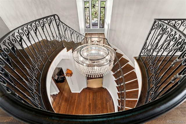 stairway featuring a notable chandelier and wood finished floors