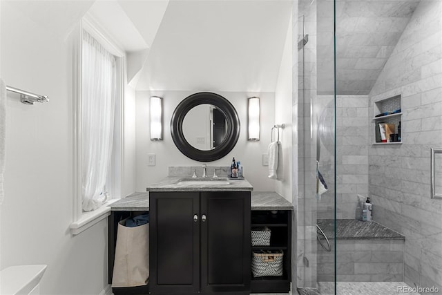 full bathroom with vaulted ceiling, a tile shower, and vanity