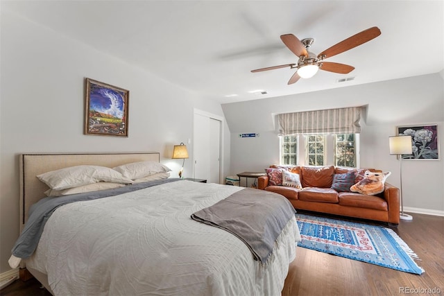 bedroom with baseboards, visible vents, ceiling fan, wood finished floors, and a closet