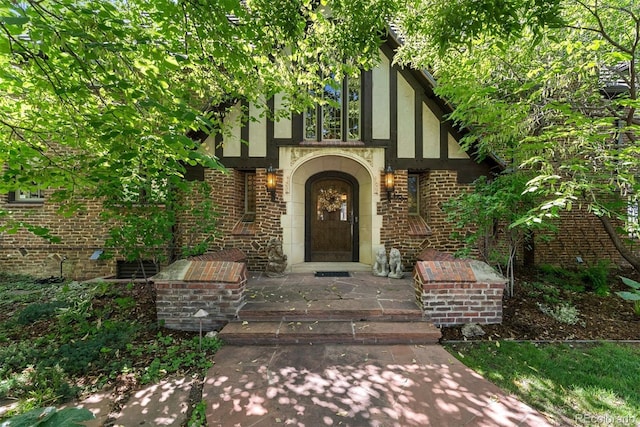 doorway to property with stucco siding and brick siding