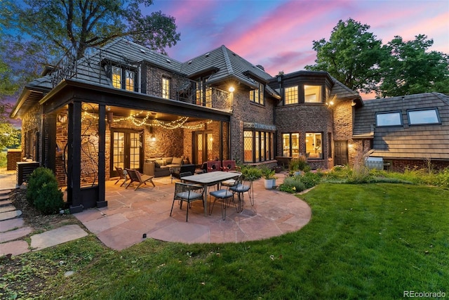 back of house at dusk with a patio area, a lawn, and an outdoor hangout area