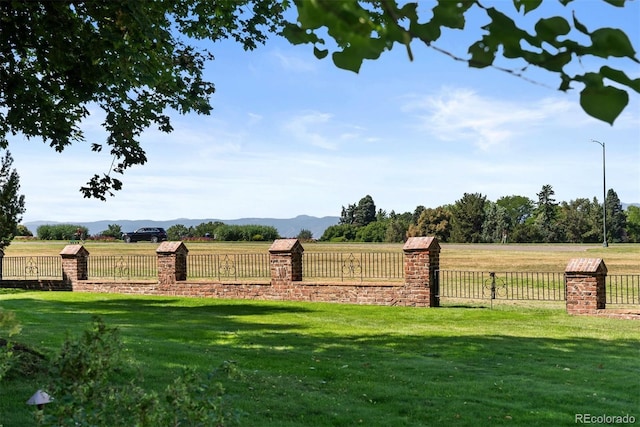 view of yard with a rural view, fence, and a mountain view