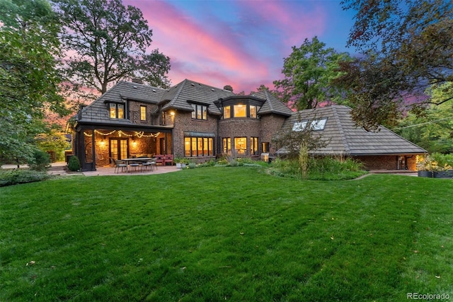back of property featuring a patio area, brick siding, and a lawn