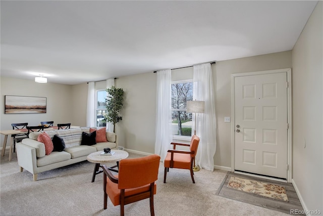 living area with light colored carpet, baseboards, and a healthy amount of sunlight