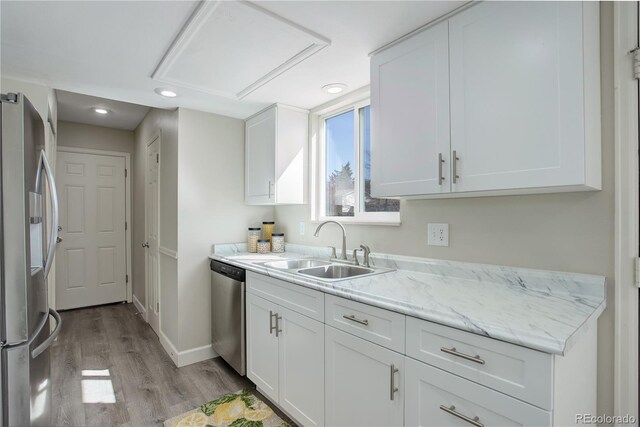 kitchen featuring white cabinets, a sink, light wood-type flooring, recessed lighting, and stainless steel appliances