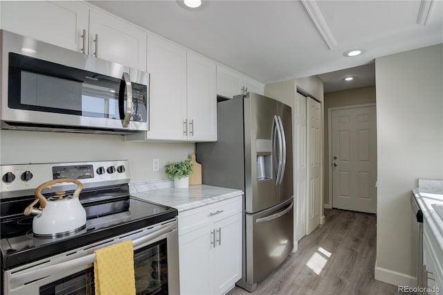 kitchen featuring white cabinets, recessed lighting, light stone counters, stainless steel appliances, and light wood finished floors