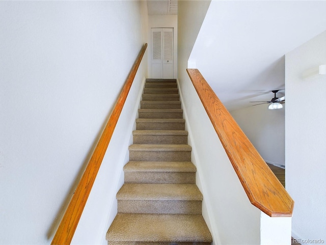 stairway featuring ceiling fan