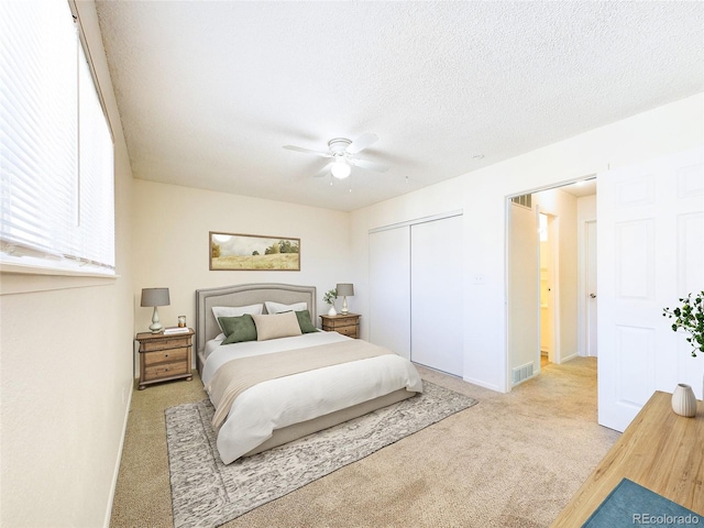 carpeted bedroom with ceiling fan, a closet, and a textured ceiling